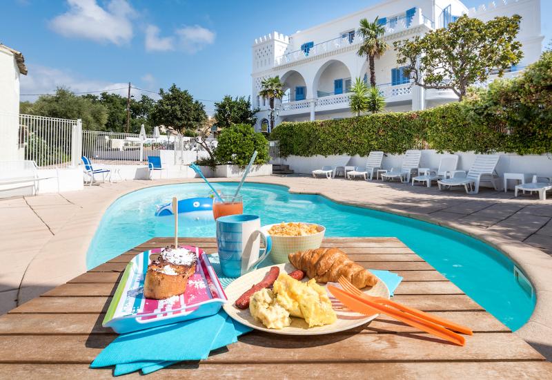 Petit déjeuner avec croissant, oeufs brouillés, gâteaux, boisson au bord de la piscine du séjour linguistique