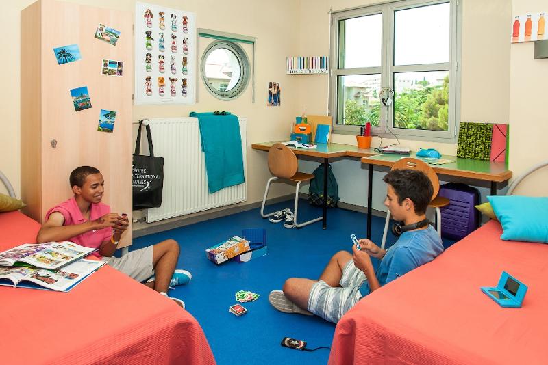 Garçons en train de jouer au UNO dans une chambre du séjour linguistique avec deux lits et deux bureaux avec des chaises