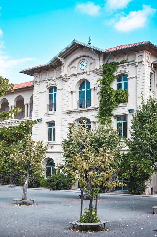 Façade du bâtiment du séjour linguistique avec une cour avec des arbres