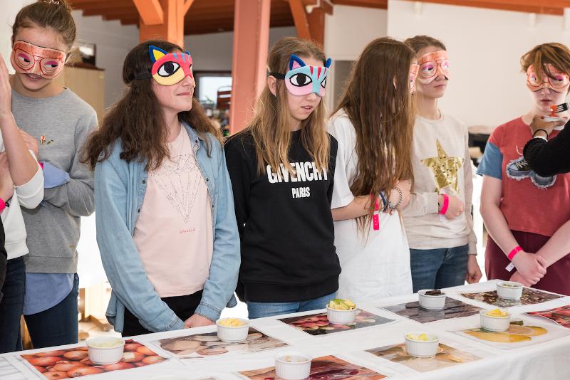 Enfants avec des masques sur les yeux pour un atelier du séjour linguistique où ils doivent goûter à l'aveugle