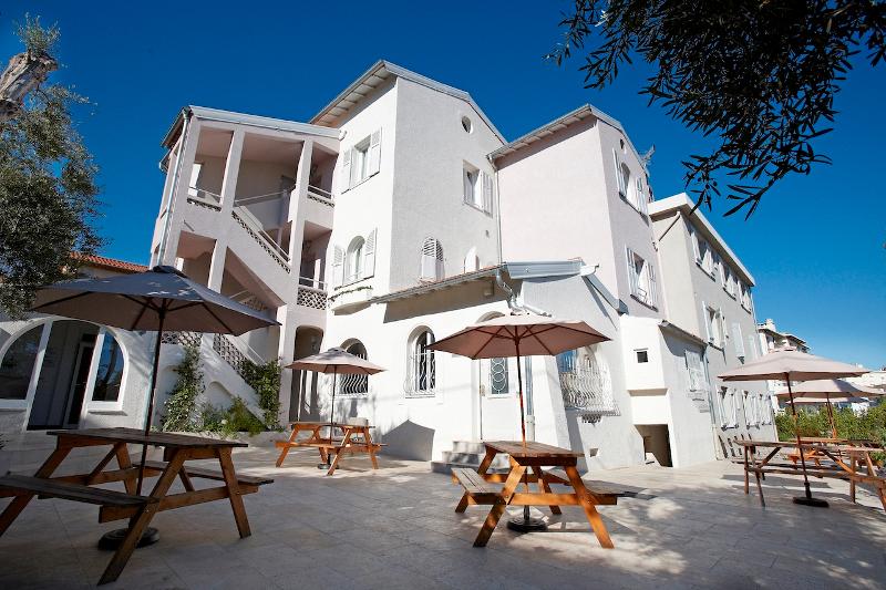 Vue de l'extérieur de la résidence premium du séjour linguistique à Antibes avec des tables de pique-nique et des parasols