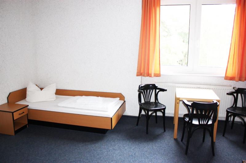 chambre individuelle du sejour linguistique allemand avec un lit, une table et trois chaises