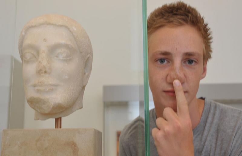 Garçon à côté de la statue d'une tête lors de la visite d'un musée pendant le sejour linguistique allemand