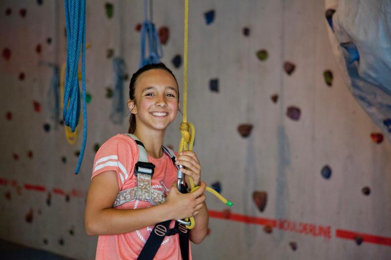 Fille avec baudrier et corde devant un mur d'escalade lors de son sejour linguistique allemand