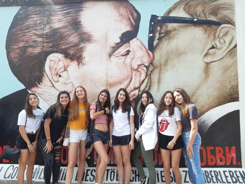 Groupe de jeunes filles du sejour linguistique allemand devant la célèbre peinture "Le Baiser" sur l'East Side Gallery du mur de Berlin