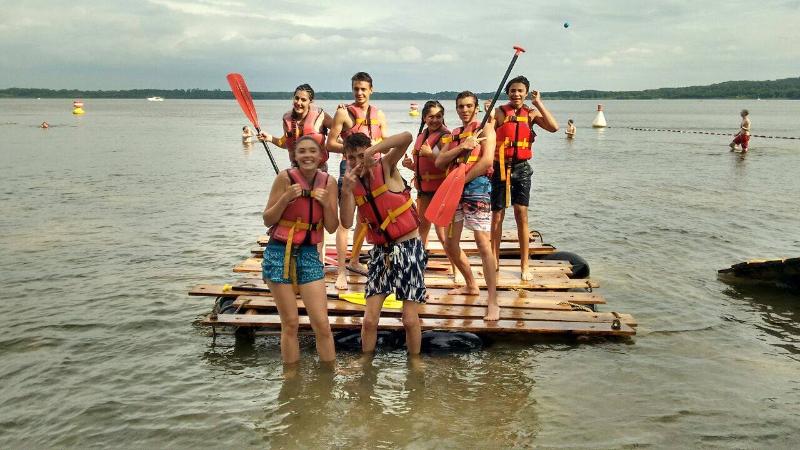 Groupe de jeunes du sejour linguistique allemand sur un radeau sur un lac avec des gilets de sauvetages et des rames 