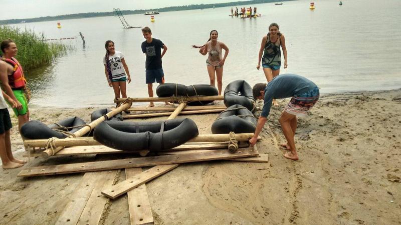 Jeunes en train de construire un radeau avec des planches de bois et des bouées pendant leur sejour linguistique allemand