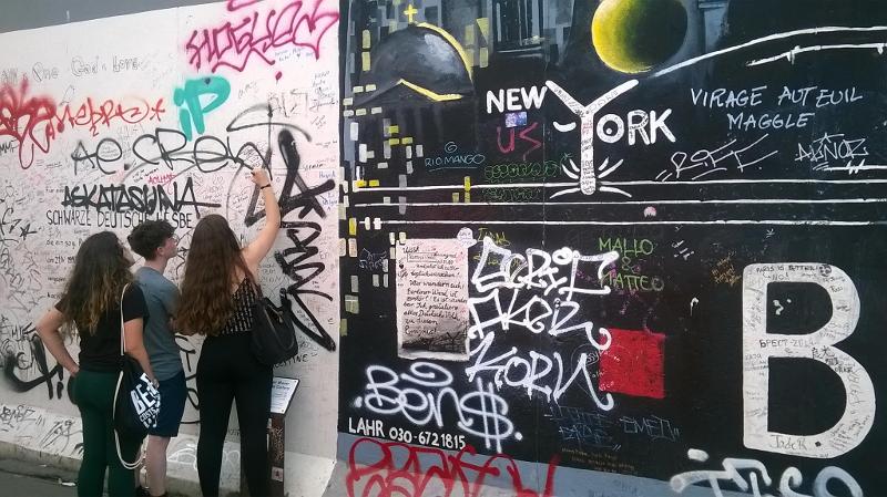 Jeunes fille qui écrivent sur un mur dans la partie westend du mur de Berlin lors d'une sortie du sejour linguistique allemand