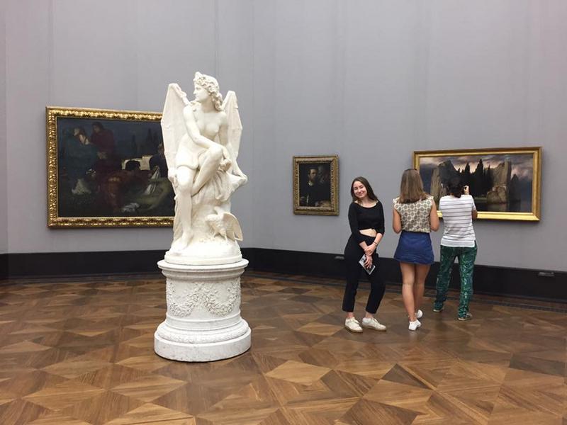 3 filles dans un musée avec une statue d'ange au milieu de la pièce et des tableaux aux murs pendant leur sejour linguistique allemand