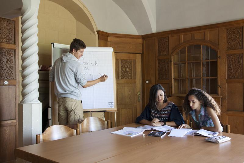 des élèves qui révise dans une salle de classe avec un garçon qui écrit au tableau