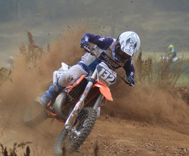 un jeune en motocross descend une pente avec de la boue pendant une colonie de vacances sports mécaniques 