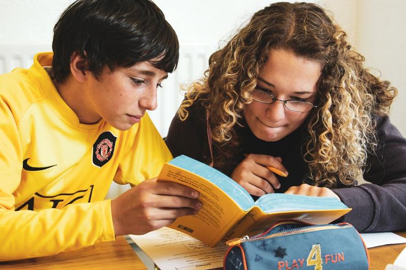 une fille et un garçon en train de regarder un dictionnaire pendant un cours du voyage linguistique angleterre
