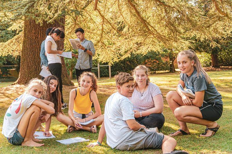 Groupe de jeunes en extérieur en train de réviser les cours de langue du voyage linguistique angleterre