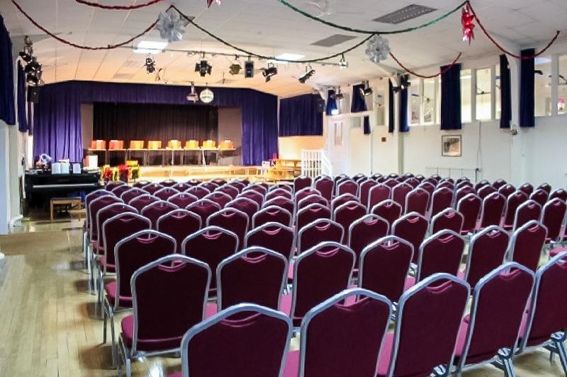 Salle de conférence du voyage linguistique angleterre avec des rangs de chaises violettes et une estrade