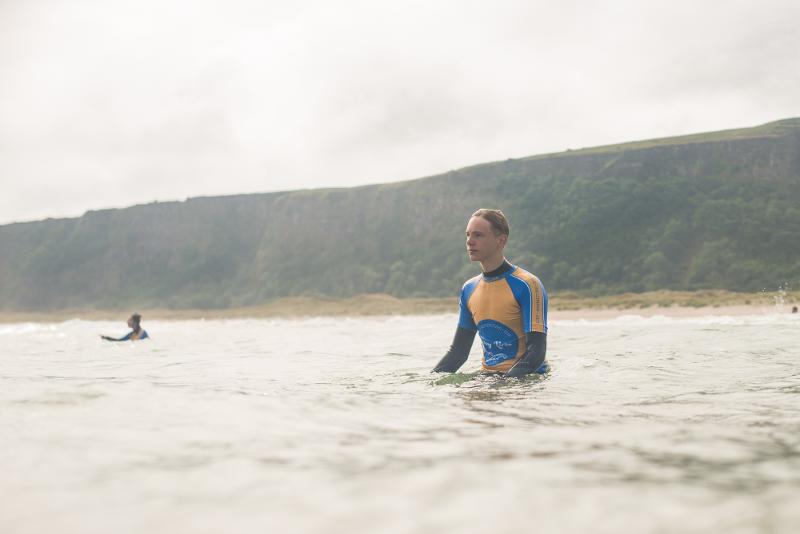garçon du séjour linguistique irlande dans l'eau attendant une vague 