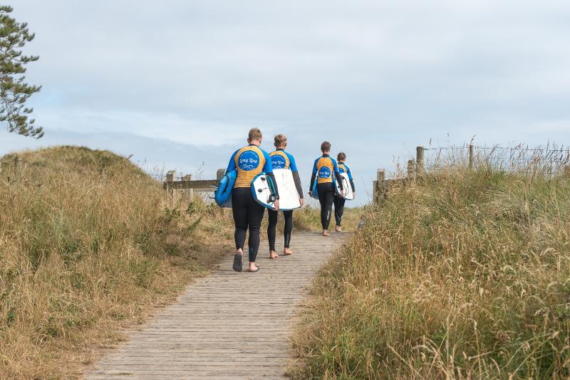 jeunes avec des planches de surf sur le chemin menant à la plage du séjour linguistique irlande 