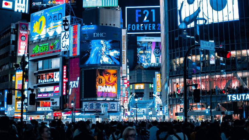 quartier avec pleins de panneaux publicitaires et du monde en colonie au japon