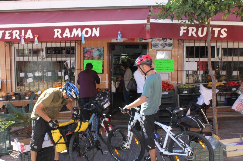 Deux personnes en vélo devant une boutique de fruits