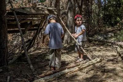 Deux enfants construisent une cabane dans la forêt lors de la colonie de vacance Occitanie