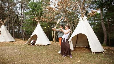 Deux enfants tire à l'arc devant trois tipis durant leur colonie de vacances