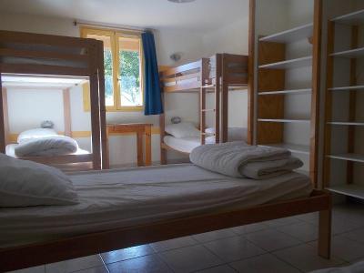 Chambre de la colonie de vacances Occitanie avec lits superposés, table de nuit, étagères, fenêtre et rideau