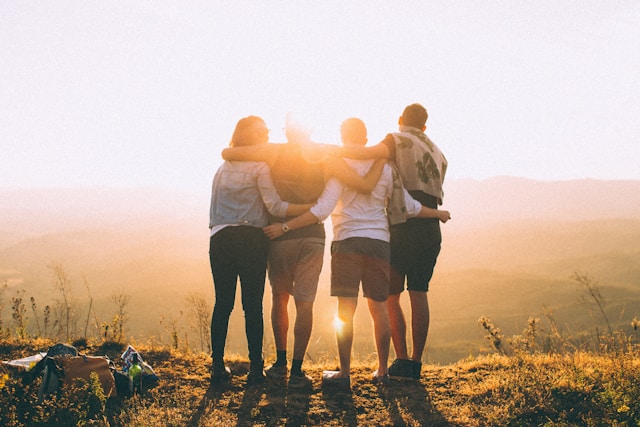 4 jeunes de dos face à un coucher de soleil